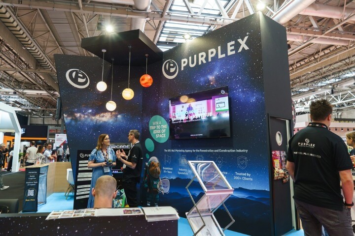 Purplex Marketing exhibition stand at FIT Show 2025 featuring staff, branding, and a space-themed display for construction and fenestration marketing.