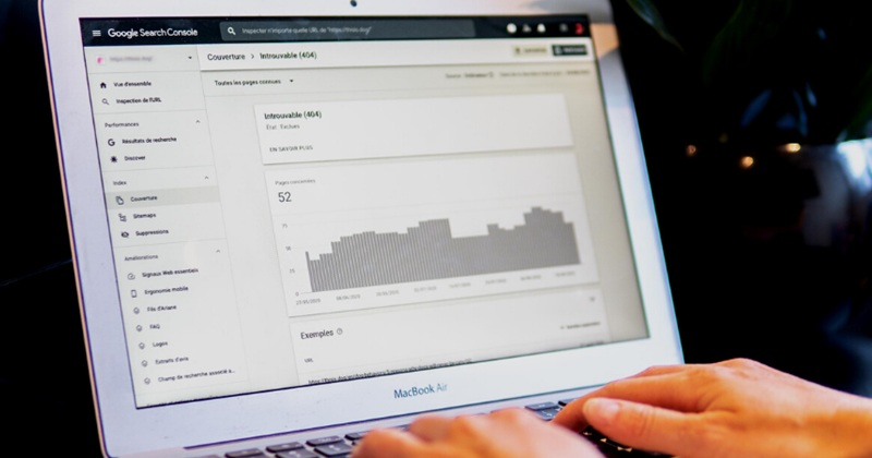 A person using Google Search Console on a MacBook Air, reviewing a 404 error report related to website performance and SEO.