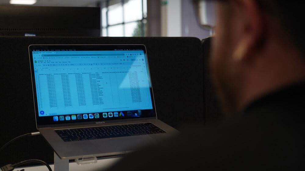 PPC management build stage creating ads, keywords, and budgets on laptop spreadsheet