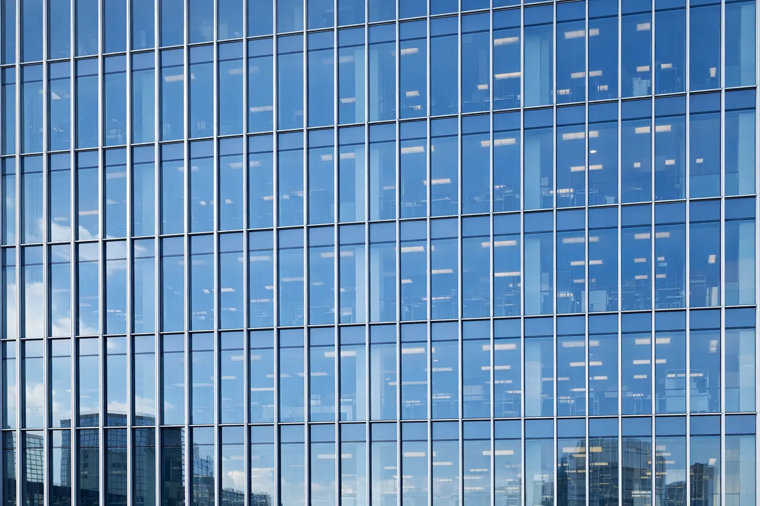 Curtain wall systems forming a glazed commercial building façade with aluminium mullions and reflective glass panels