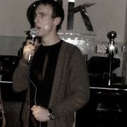 AI automation specialist Ryan Wheadon speaking into a microphone at a live event